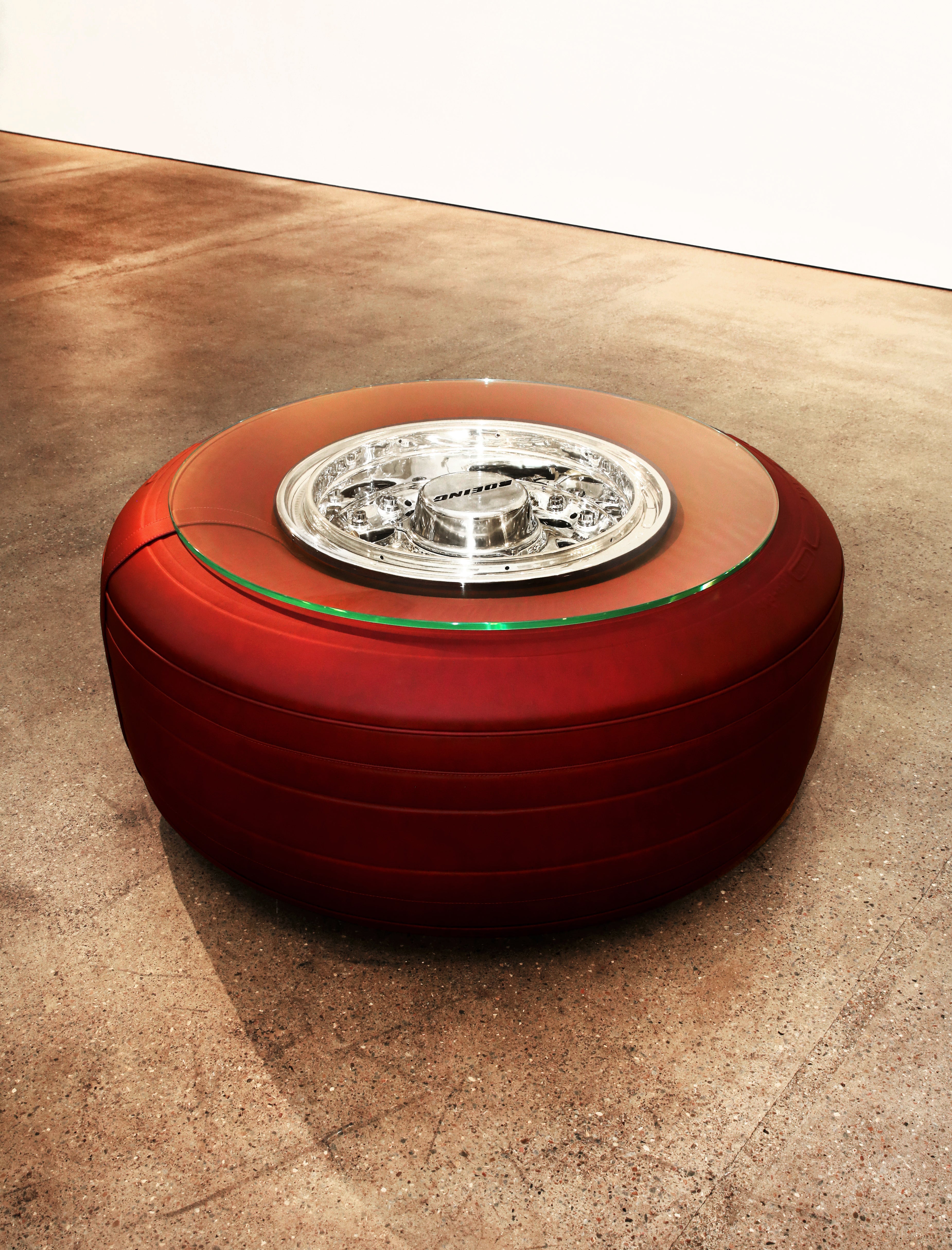 A Boeing 747 wheel coffee table with tire wrapped in red leather at gallery.